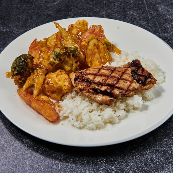 Grilled chicken, tempura vegetables, and white rice with sesame seeds on a white plate.