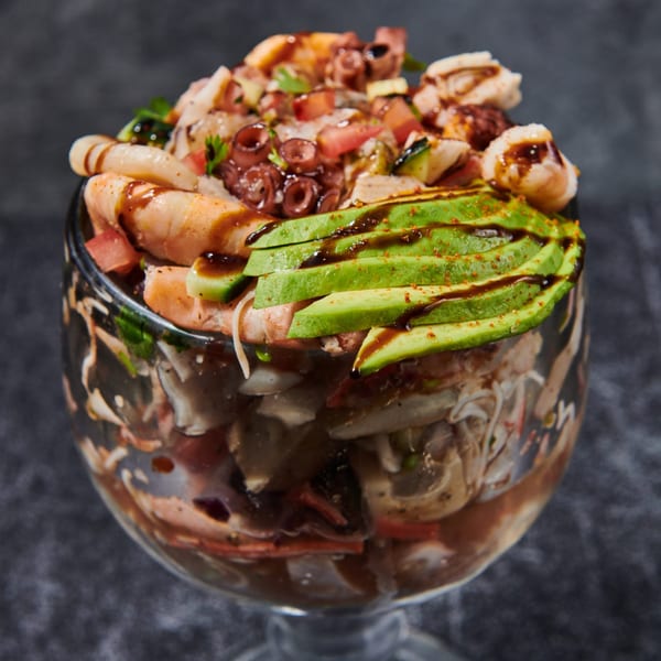 El Sushi Loco's seafood cocktail with shrimp, octopus, avocado, and sauce in a large glass.